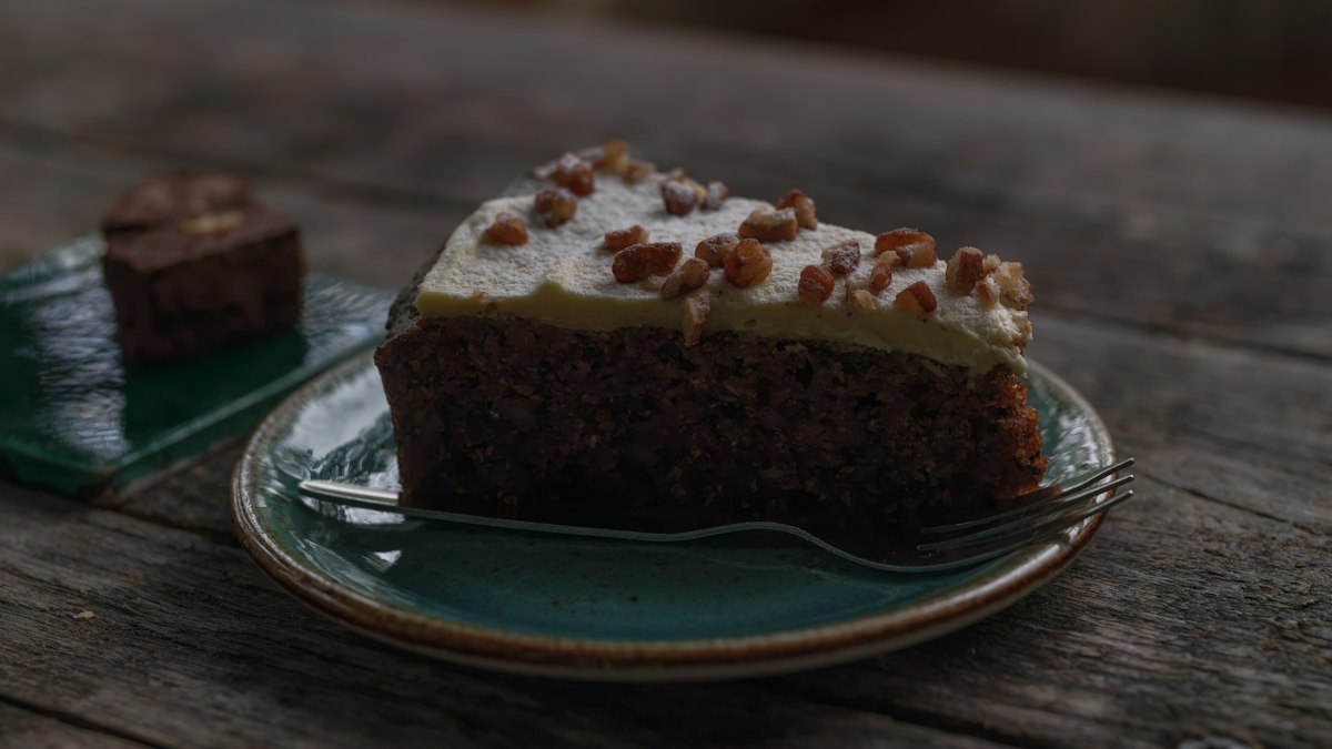 Pedazo de pastel de zanahoria con crema de queso y nueces sobre un plato, el tipo de producto específico que busca un cliente